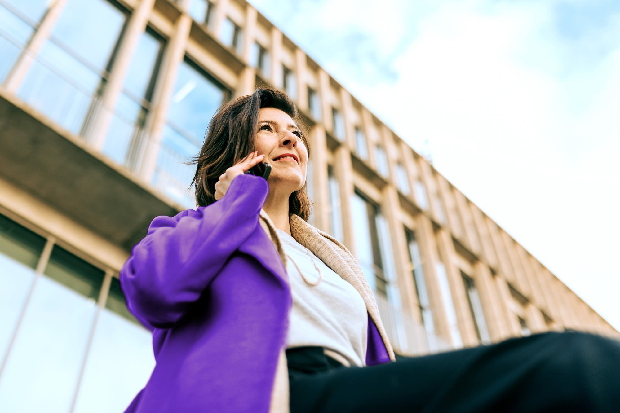 Frau telefoniert vor Bürogebäude – Komfort-Konto für moderne Geschäftskunden. Frau telefoniert vor Bürogebäude – Komfort-Konto für moderne Geschäftskunden.