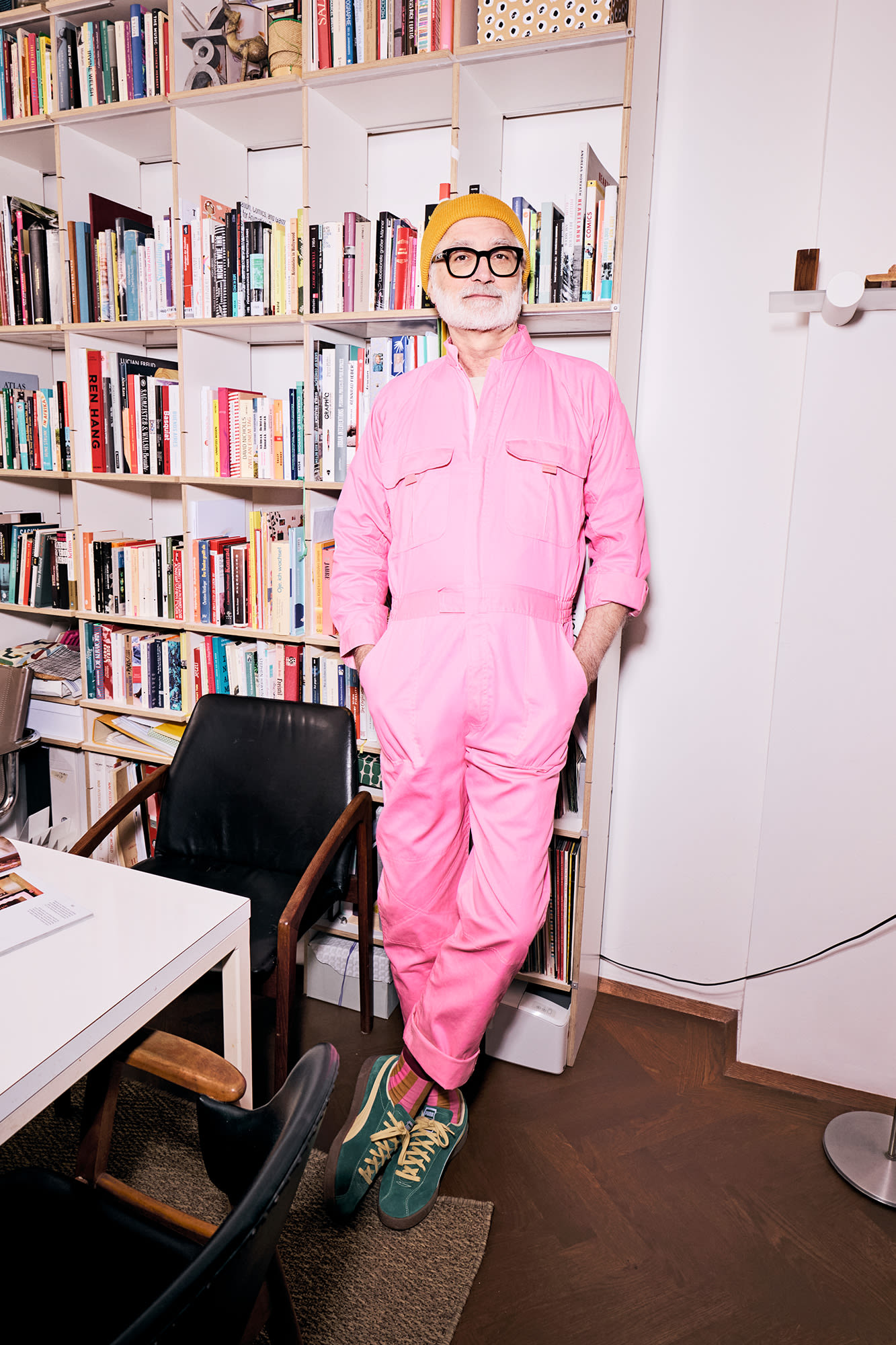 Mann mit rosa Jumpsuit steht an Bücherregal -Silberkredite bei der BKS Bank Mann mit rosa Jumpsuit steht an Bücherregal -Silberkredite bei der BKS Bank