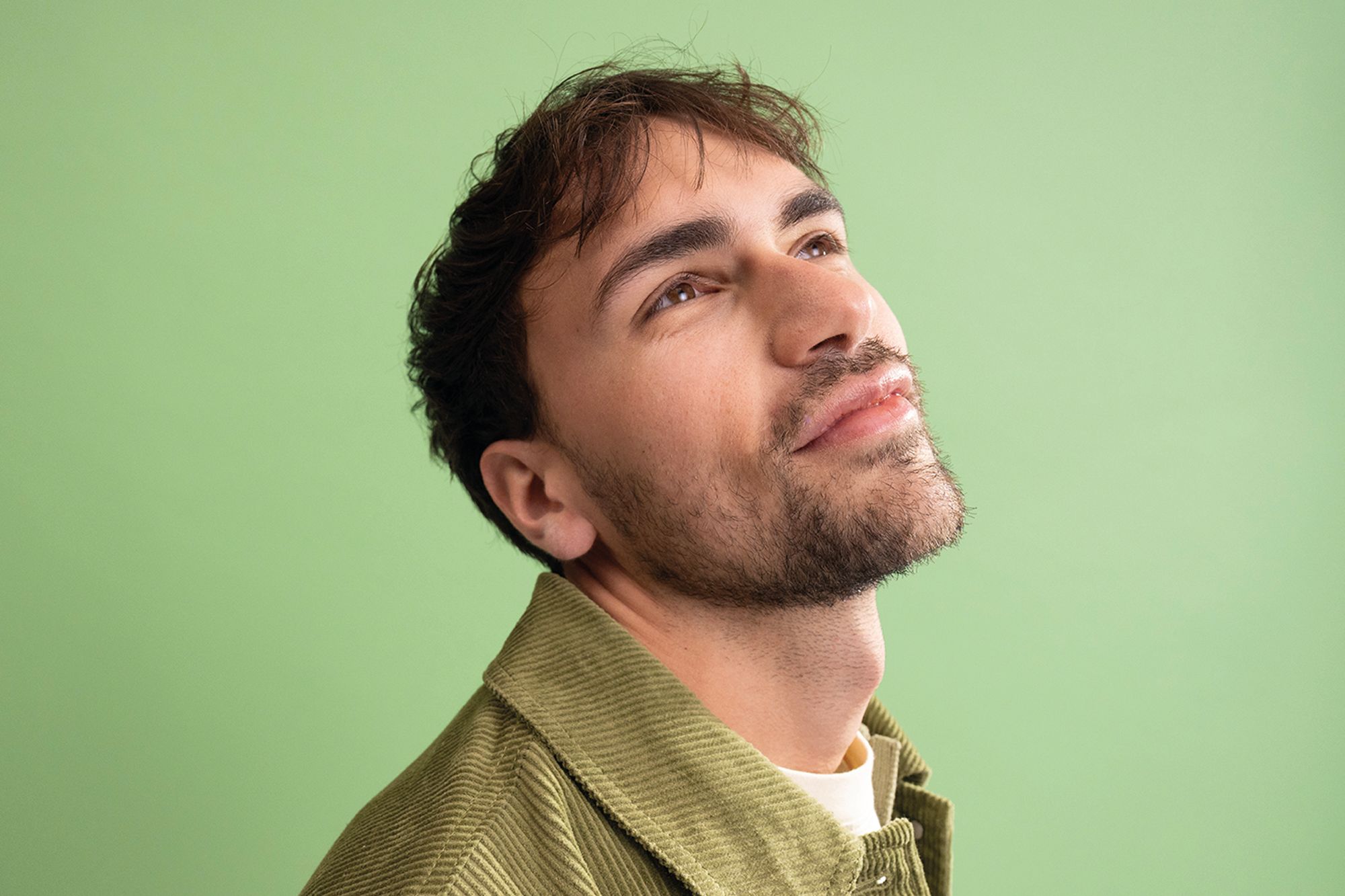 Junger Mann vor grünem Hintergrund mit Blick Richtung Decke. Junger Mann vor grünem Hintergrund mit Blick Richtung Decke.