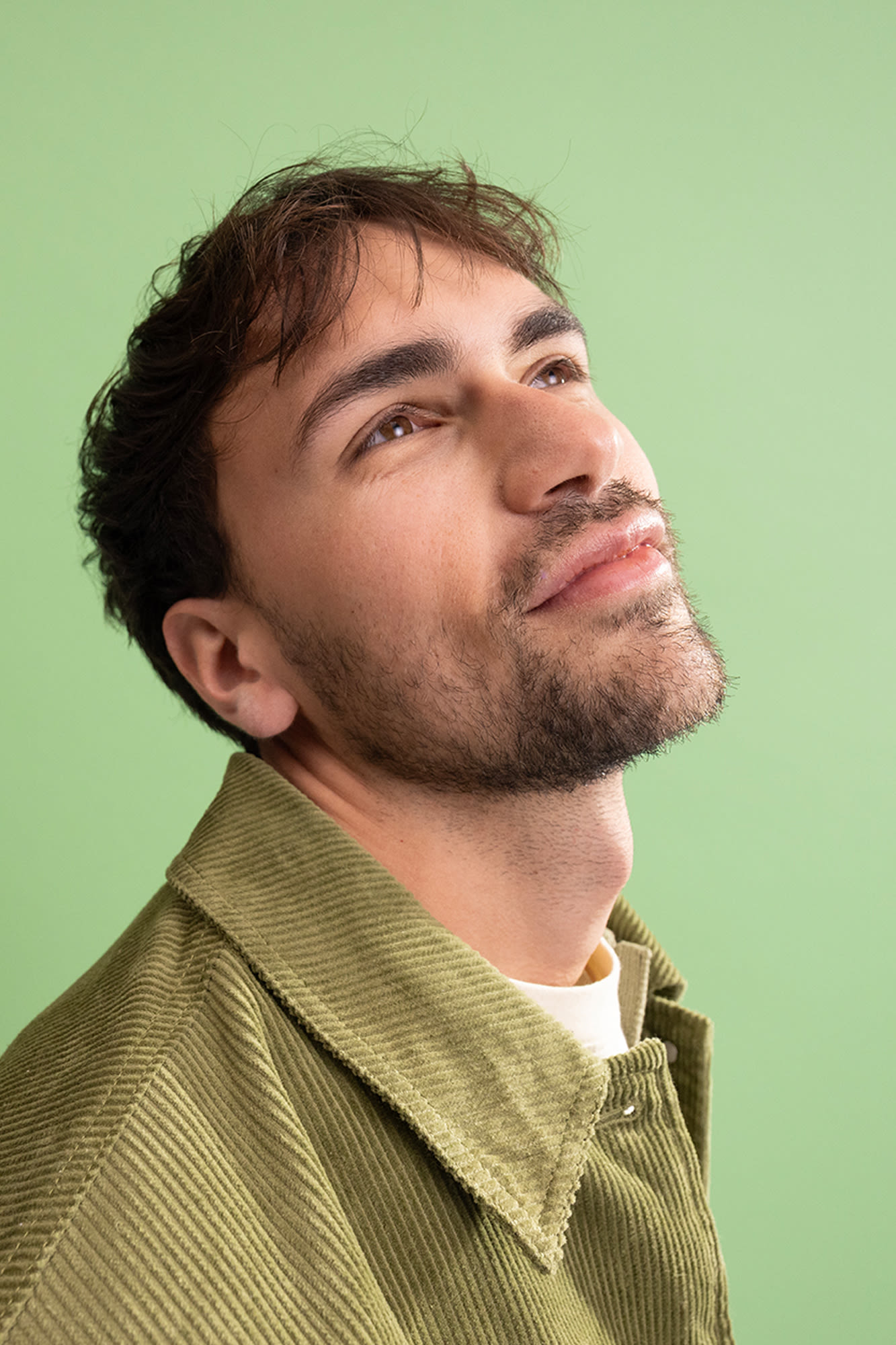 Junger Mann vor grünem Hintergrund mit Blick Richtung Decke. Junger Mann vor grünem Hintergrund mit Blick Richtung Decke.